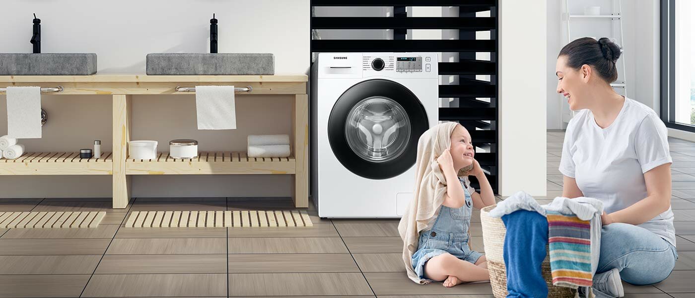 Dwójka rodziców i dziecko wykładają z pralki czyste ubrania Dwójka rodziców i dziecko wykładają z pralki czyste ubrania