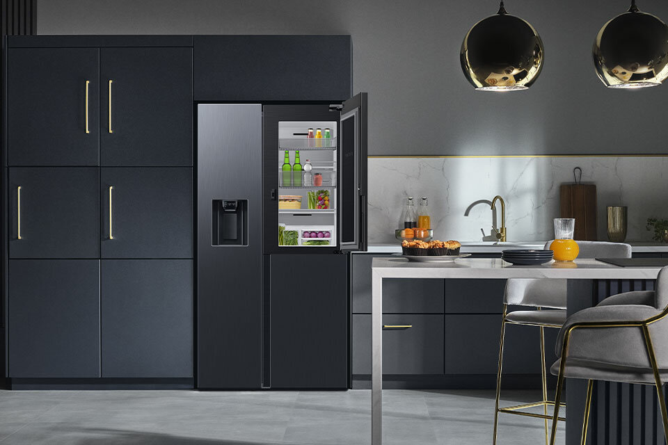 Zdjęcie eleganckiej kuchni, w której stoi lodówka Samsung w kolorze grafitowej stali. Zdjęcie eleganckiej kuchni, w której stoi lodówka Samsung w kolorze grafitowej stali.