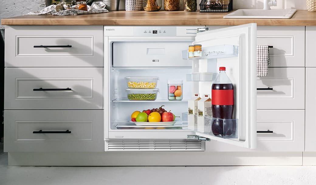Otwarta lodówka MPM-116-CJI-17/E w jasnej zabudowie kuchennej.