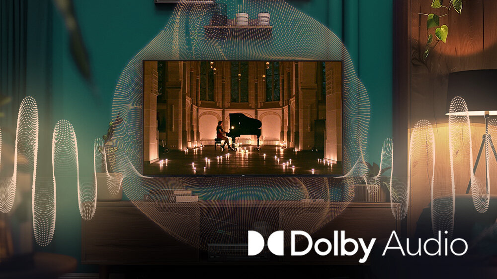 Telewizor JVC LT-65VD3500 - Pełne brzmienie z Dolby Audio, obraz pokazujący faune morską z rybami, telewizor stojący na stoliku z którego wydobywa się dźwięk
