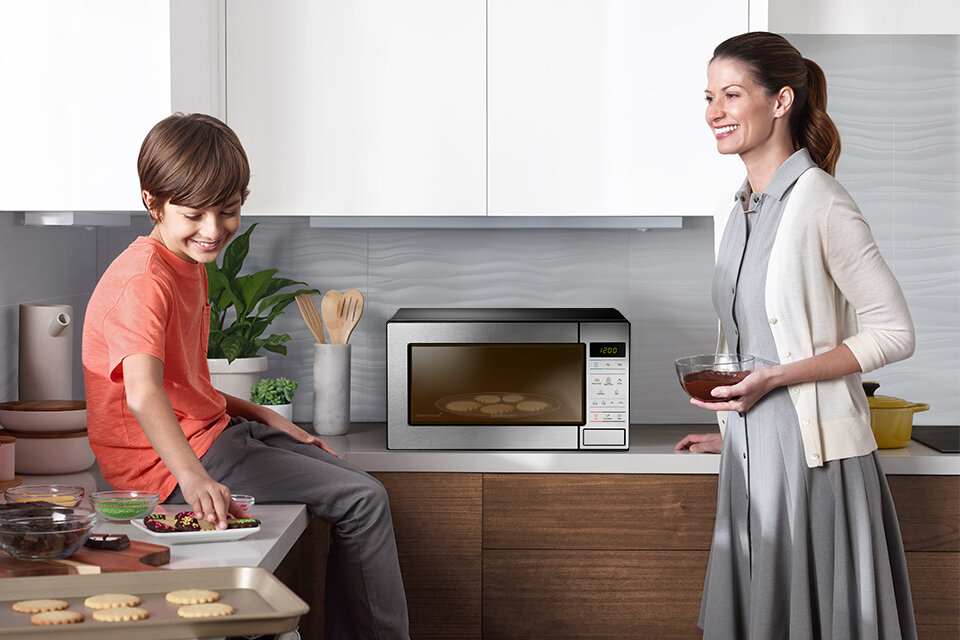 Matka z dzieckiem przygotowująca deser w kuchence mikrofalowej Matka z dzieckiem przygotowująca deser w kuchence mikrofalowej